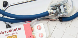 Vasodilatateurs : tout savoir sur ces médicaments antihypertenseurs Vasodilating drug for heart and blood vessels Packing of pills with inscription "Vasodilatator Medication" for treatment of cardiovascular diseases is at doctor cardiologist near EKG and stethoscope