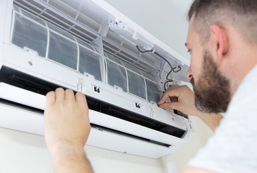 Male technician cleaning air conditioner indoors technician service cleaning the conditioner, filter change