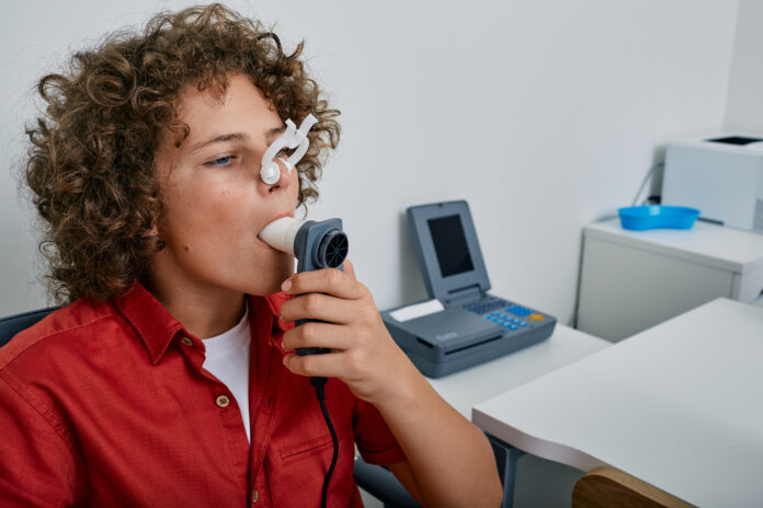 Curly boy performing pulmonary function test and spirometry using spirometer at medical clinic Spirometry of child's lungs