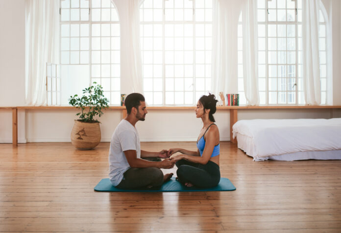 Beautiful young couple doing yoga at home