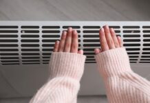 Syndrome de Raynaud : quelles sont les causes ? Woman warming hands near electric heater at home, top view