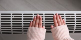 Syndrome de Raynaud : quelles sont les causes ? Woman warming hands near electric heater at home, top view