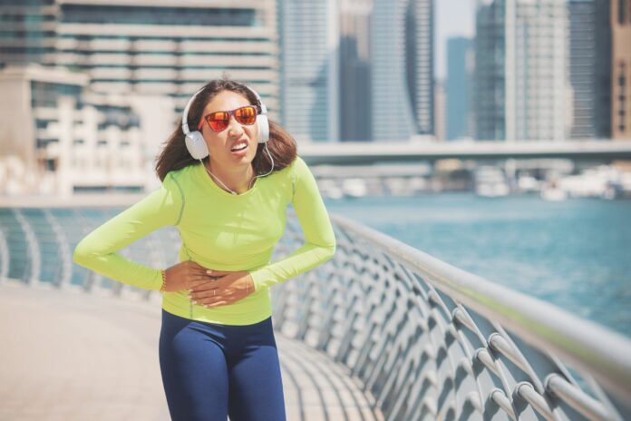 Suffering woman on a jog is experiencing severe pain in her side Fitness and sports exercises during diseases of the liver, spleen and stomach ulcer
