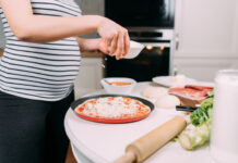 Mozzarella : peut-on en manger quand on est enceinte ? close up details of pregnant woman making home pizza