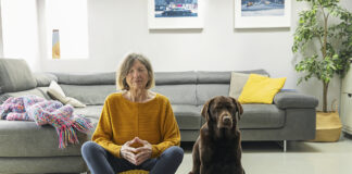 Qu’est-ce que la zoothérapie ? Senior woman meditating at home with her pet dog