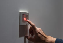 Dormir sans chauffer : une option judicieuse ? Man adjusting wall mount room thermostat