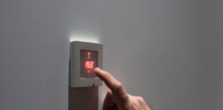 Dormir sans chauffer : une option judicieuse ? Man adjusting wall mount room thermostat