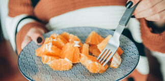 Est-il conseillé de consommer une orange en soirée ? young brunette woman eating orange slices.closeup