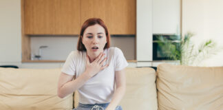 Comment le stress peut-il entraîner une sensation de souffle court ? Young woman alone at home with a panic attack shortness of breath, trembling, numbness, loss of consciousness. Front view of a female suffering an anxiety sitting on a couch. chest pain, fear symptom