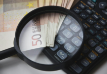 Immobilier à l’étranger : déclarez-le sans tarder ! Loupe zoomant sur un billet de 50 euros et une calculatrice pour symboliser le contrôle fiscal et la déclaration des revenus immobiliers à l'étranger.