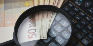 Immobilier à l’étranger : déclarez-le sans tarder ! Loupe zoomant sur un billet de 50 euros et une calculatrice pour symboliser le contrôle fiscal et la déclaration des revenus immobiliers à l'étranger.