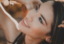 Alimentation et éclat : les secrets d’un teint parfait Portrait lumineux d'une jeune femme souriante et radieuse, regardant vers le haut, avec un visage éclatant et des yeux bleus dans une chaude lumière du soleil.